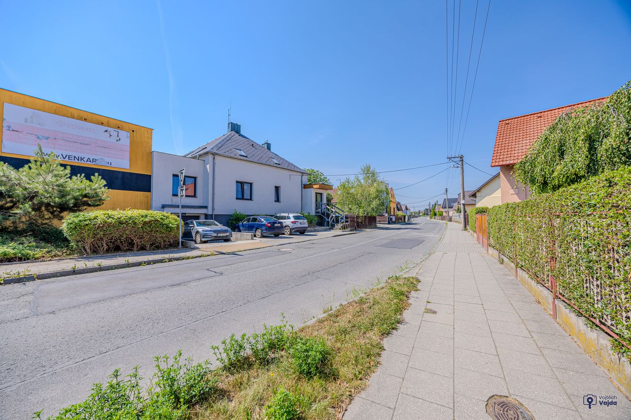Ulice s chodníkem, v pozadí dům