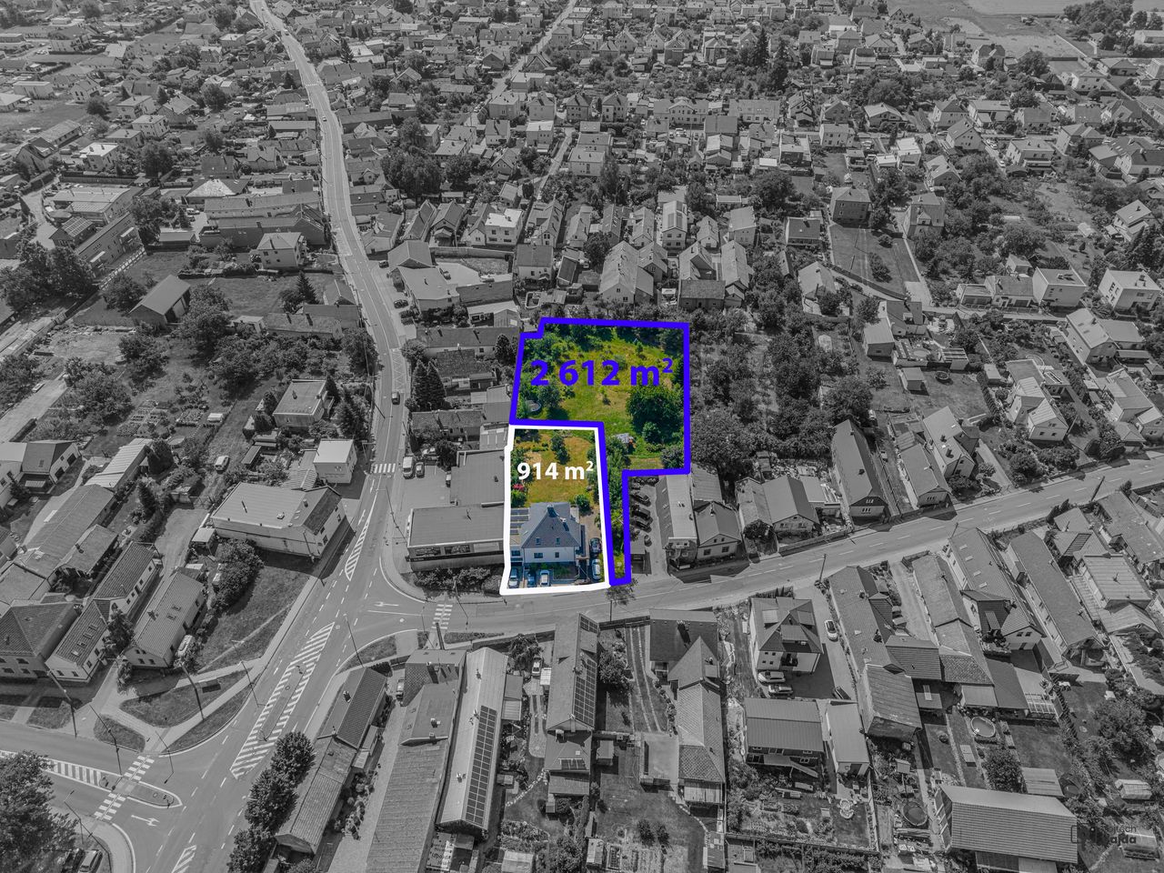 Letecký snímek s bíle vyznačeným domem se zahradou 914 m² a modře vyznačenými navazujícími pozemky 2 612 m²